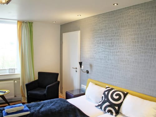Modernes Hotelzimmer mit stilvollem Dekor, einem gemütlichen Bett und einem Sessel.