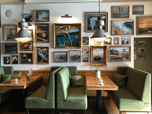 Gemütliche Restaurant-Ecke mit grünen Sitzbänken und maritimen Bildern an der Wand
