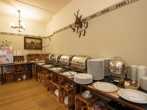 Frühstücksbuffetbereich mit Geschirr und Chafing Dishes in einem gemütlichen Restaurant.