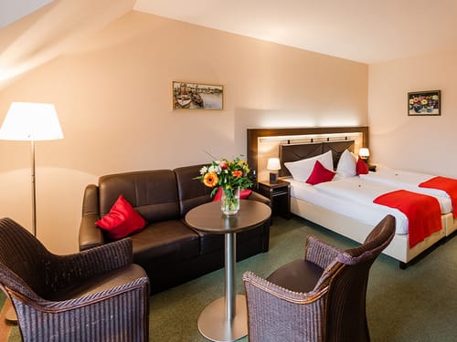 Doppelzimmer mit Twinbett, Couch, Sessel, Tisch und Stehlampe
