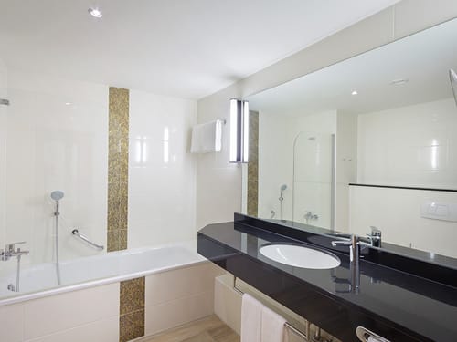 Badbereich mit Badewanne, Waschtisch und großen Wandspiegel