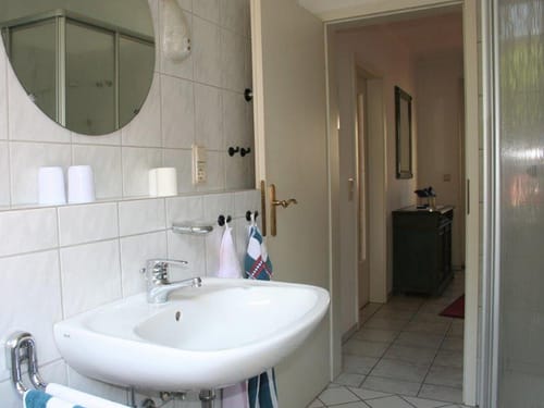 Badbdereich mit Wandspiegel, Dusche und Waschtisch
