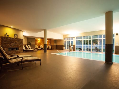 Wellnesslandschaft mit Pool und Relaxliegen am Rande