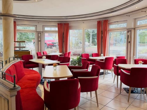 Hotelrestaurant mit verschiedenen Tischgruppen und roten Sesseln