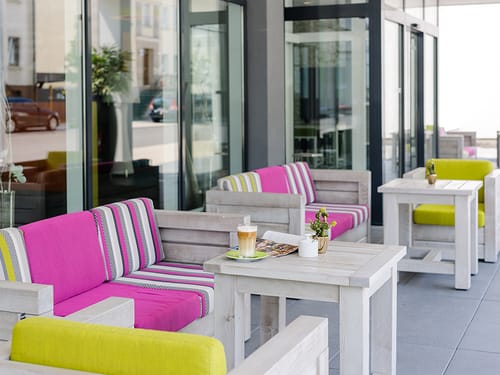 Hotel Terrasse mit Gartenmöbeln aus Holz und bunten Polstern