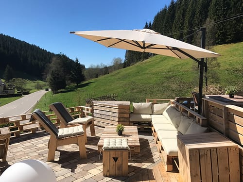 Gemütliche Terrasse im Garten mit Sonnenschirm und Terrassenmöbeln