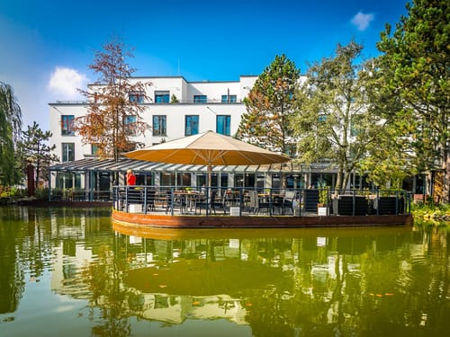 Modernes Gebäude mit Terrasse über einem See im Herbst.