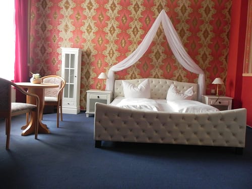 Himmelbett, Nachttisch, zwei Sessel und ein kleiner Tisch im Doppelzimmer