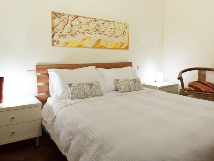 einfaches Doppelzimmer mit Doppelbett, Sessel und Nachttischen