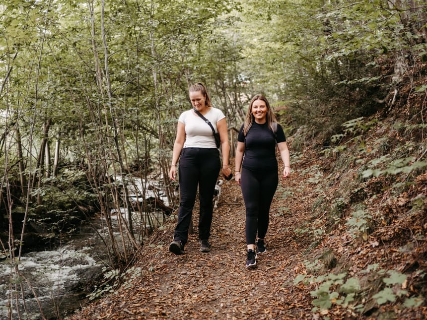 Zwei Frauen wandern auf einem Waldweg.