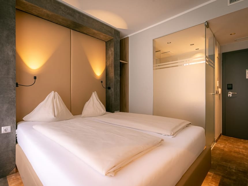 Modernes Hotelzimmer mit einem Doppelbett und stimmungsvoller Beleuchtung.