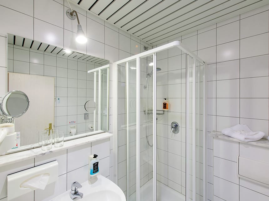 Badbereich mit Waschtisch, Dusche, WC und Wandspiegel