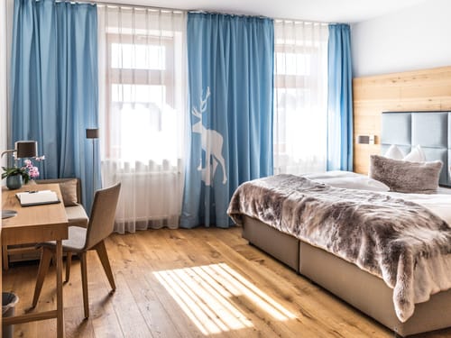 Alpines Hotelzimmer mit Doppelbett und Hirsch-Dekor – Gemütliche Unterkunft im Landhausstil