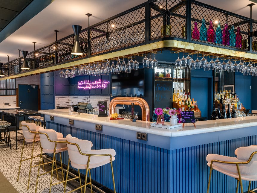 Moderne Bar mit eleganten blau-goldenen Akzenten und stilvollen Hockern