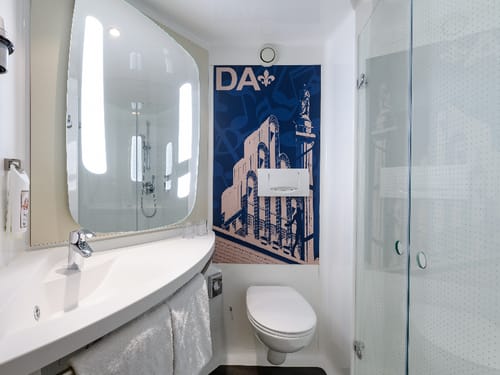 Modernes Badezimmer mit Glasdusche, Waschbecken und blauem Poster.