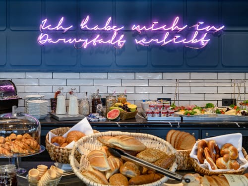 Frühstücksbuffet mit diversen Backwaren und Neon-Schriftzug "Ich habe mich in Darmstadt verliebt".