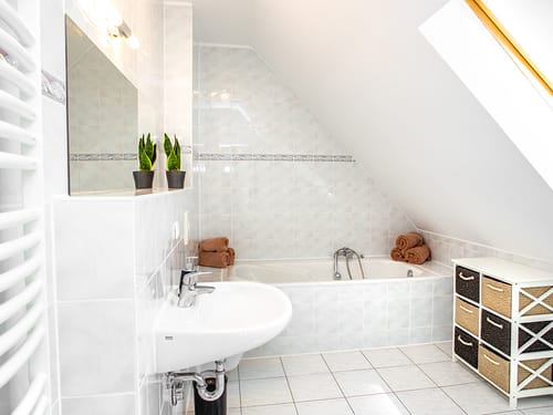 Badbereich mit Wandspiegel, Waschtisch und Badewanne