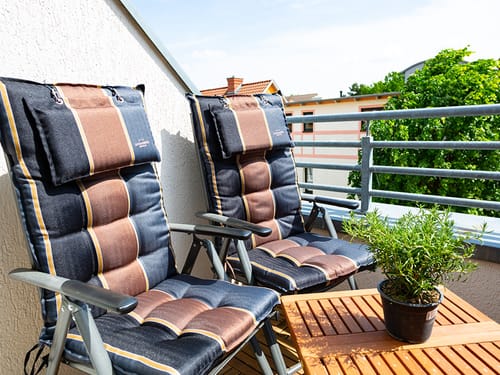 zwei Gartenstühle mit Auflage und kleiner Tisch auf dem Balkon