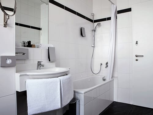 Badbereich mit Wandspiegel, Waschtisch und Badewanne