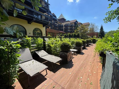 Entspannte Sonnenliegen auf einer begrünten Terrasse vor einem Hotelgebäude.