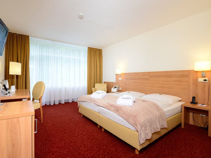 Doppelzimmer mit Doppelbett, Schreibtisch, Stuhl und TV an der Wand