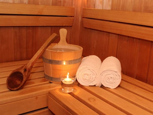 Handtücher, Aufgusseimer und Kerze in der Sauna