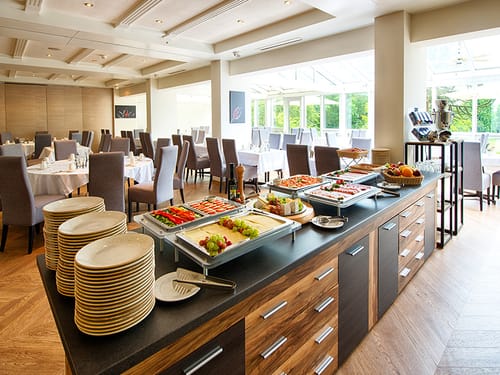 Speisenbuffet und gedeckte Tische im Frühstücksraum