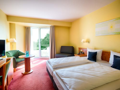 gemütliches Doppelzimmer mit Sesseln, Tisch, Schreibtisch, Stuhl und TV