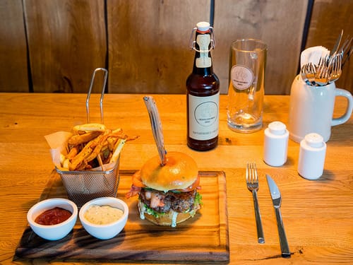 Gedeckter Tisch mit Pommes, Burger, Salz,Pfeffer und einer Flasche Bier