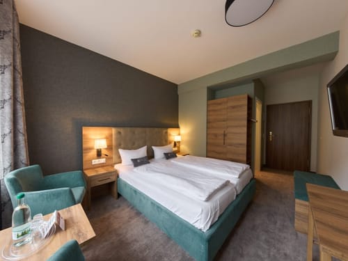 Helles Zimmer mit TV, Schreibtisch und zwei Stühlen