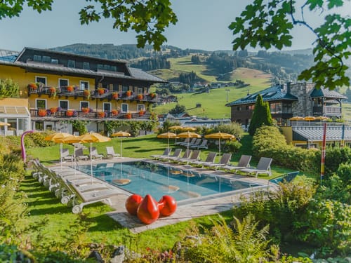 großer Pool mit Relaxliegen im Garten des Saalbacher Hofes