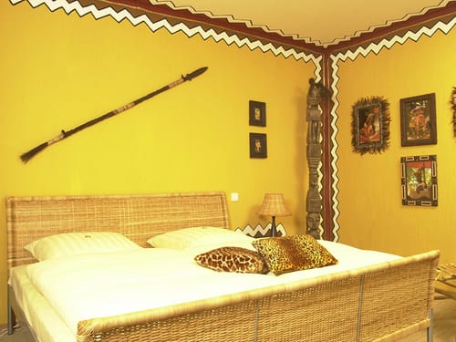 Doppelbett aus Rattan mit verschiedenen Dekoartikeln an der Wand