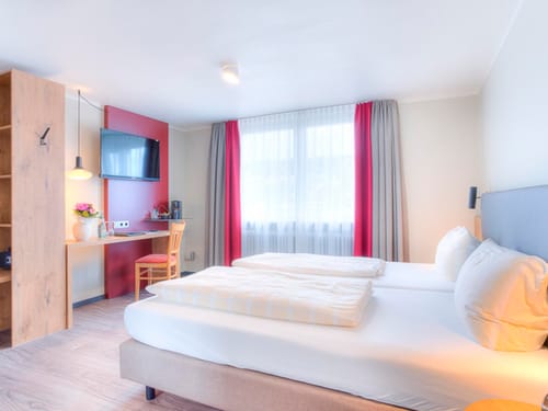 Standard Zimmer mit Doppelbett, Schreibtisch, TV und Stuhl