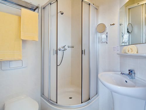 Badezimmer mit Dusche, Waschtisch, Kosemtik und Wandspiegel