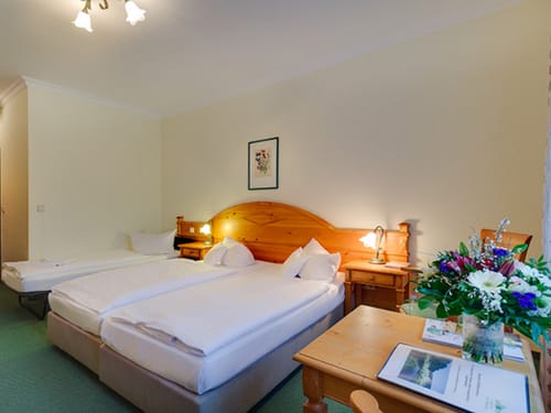 geräumiges Doppelzimmer mit Zustellbett, Tisch und zwei Stühlen