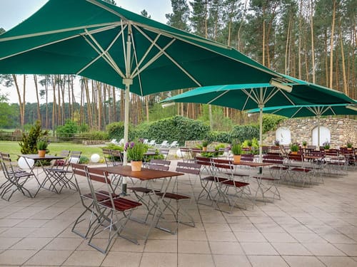 Gemütliche Außenterrasse mit Sonnenschirmen und Sitzbereich in einem Waldgebiet
