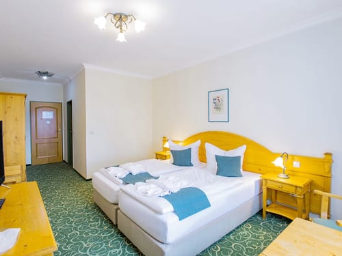 Gemütliches Hotelzimmer mit Doppelbett und warmem Holzmobiliar.