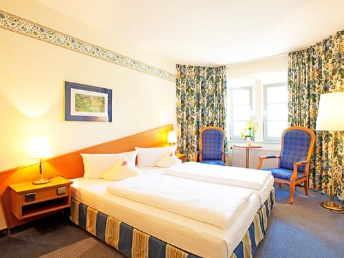 Boxspringbett, zwei Sessel und Tisch im Komfortzimmer
