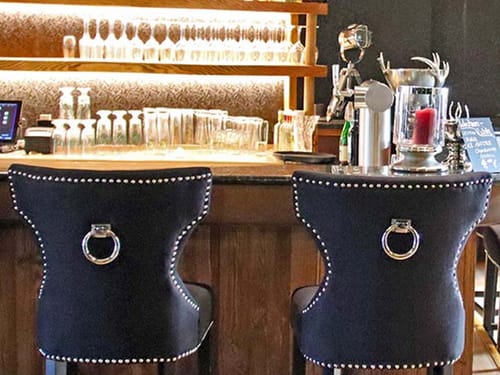 Hotel Bar mit beleuchtetem Regal im Hintergrund und Barhockern