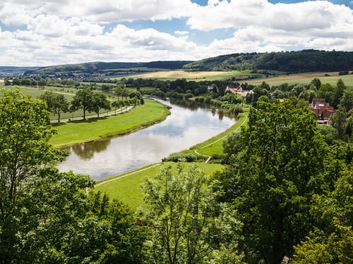 Weiter Blick über eine grüne Landschaft mit einem großem Fluss im Mittelpunkt