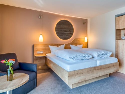 Doppelzimmer mit Doppelbett, Sessel, Tisch und Wandschrank