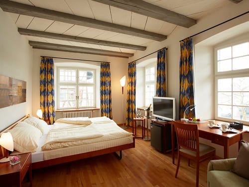 hell und elegant eingerichtetes Doppelzimmer mir Schreibtisch, Stuhl und TV