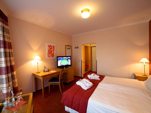 geräumiges Doppelzimmer mit Doppelbett, Schreibtisch, Stuhl und TV