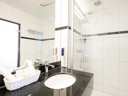 Dusche, Wandspiegel und Waschtisch im Hotelbad