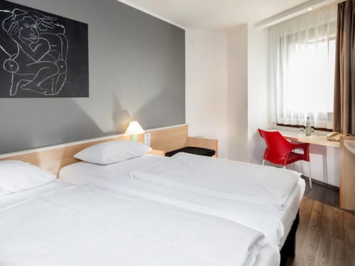 Standard Twin Room mit rotem Stuhl und Schreibtisch