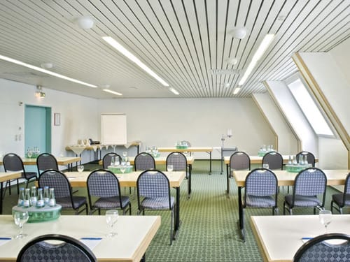 Tagungsraum mit Tischen, Stühlen, Flipchart und Projektor