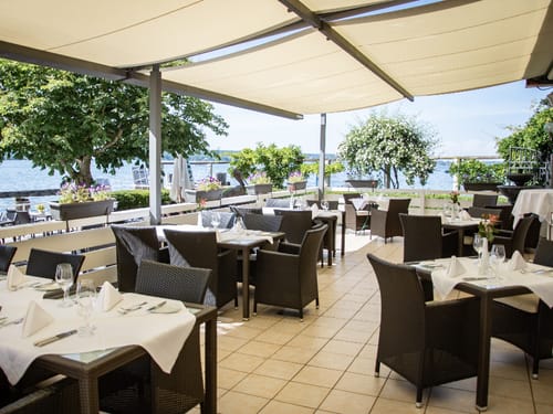 überdachte Terrasse mit gedeckten Tischgruppen im Seehotel Leoni