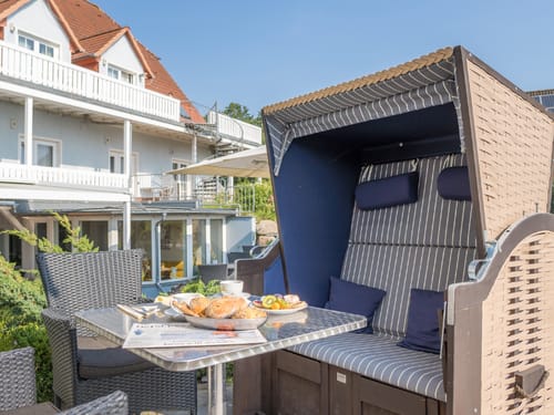 Frühstück auf der Terrasse im Strandkorb mit frischen Brötchen, Kaffee und Obst