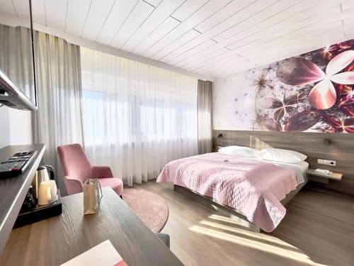 Doppelzimmer mit TV, Sessel und einem Schreibtisch