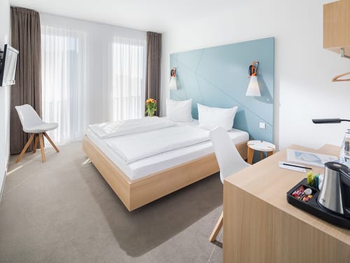 Standard Doppelzimmer mit Doppelbett, TV, Schreibtisch, Sessel und Kaffee- und Teezubereiter